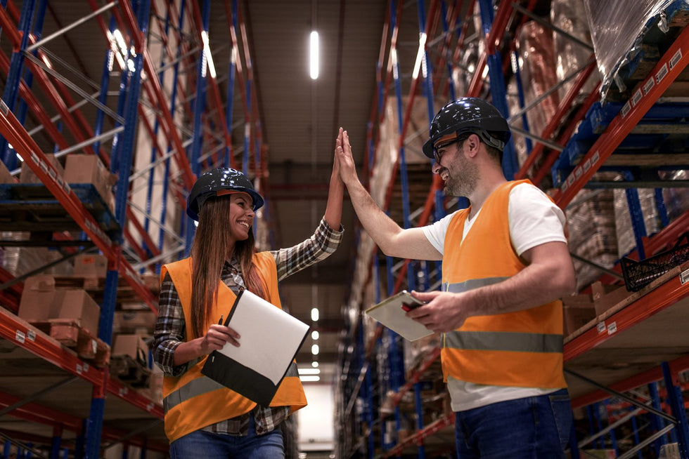 Operarios de bodega trabajando entre racks industriales